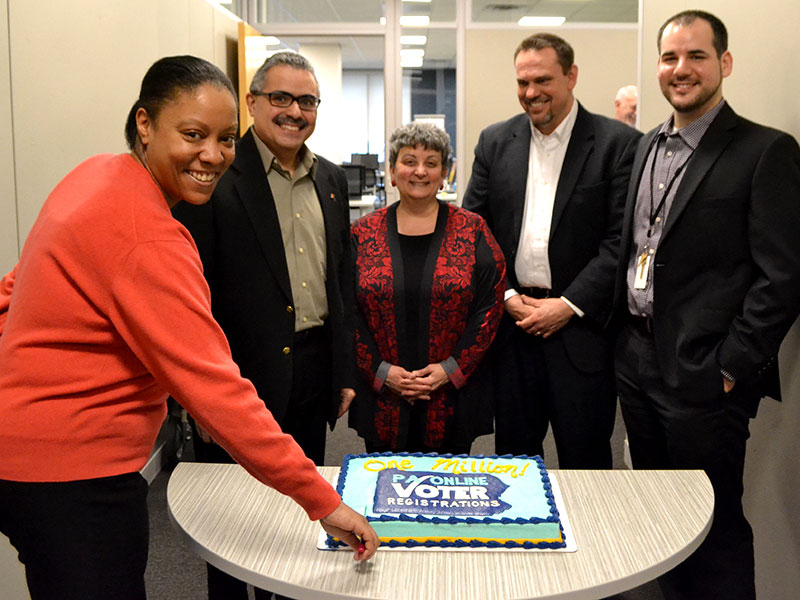 Group of election staff cutting a cake celebrating the 1 millionth registration.